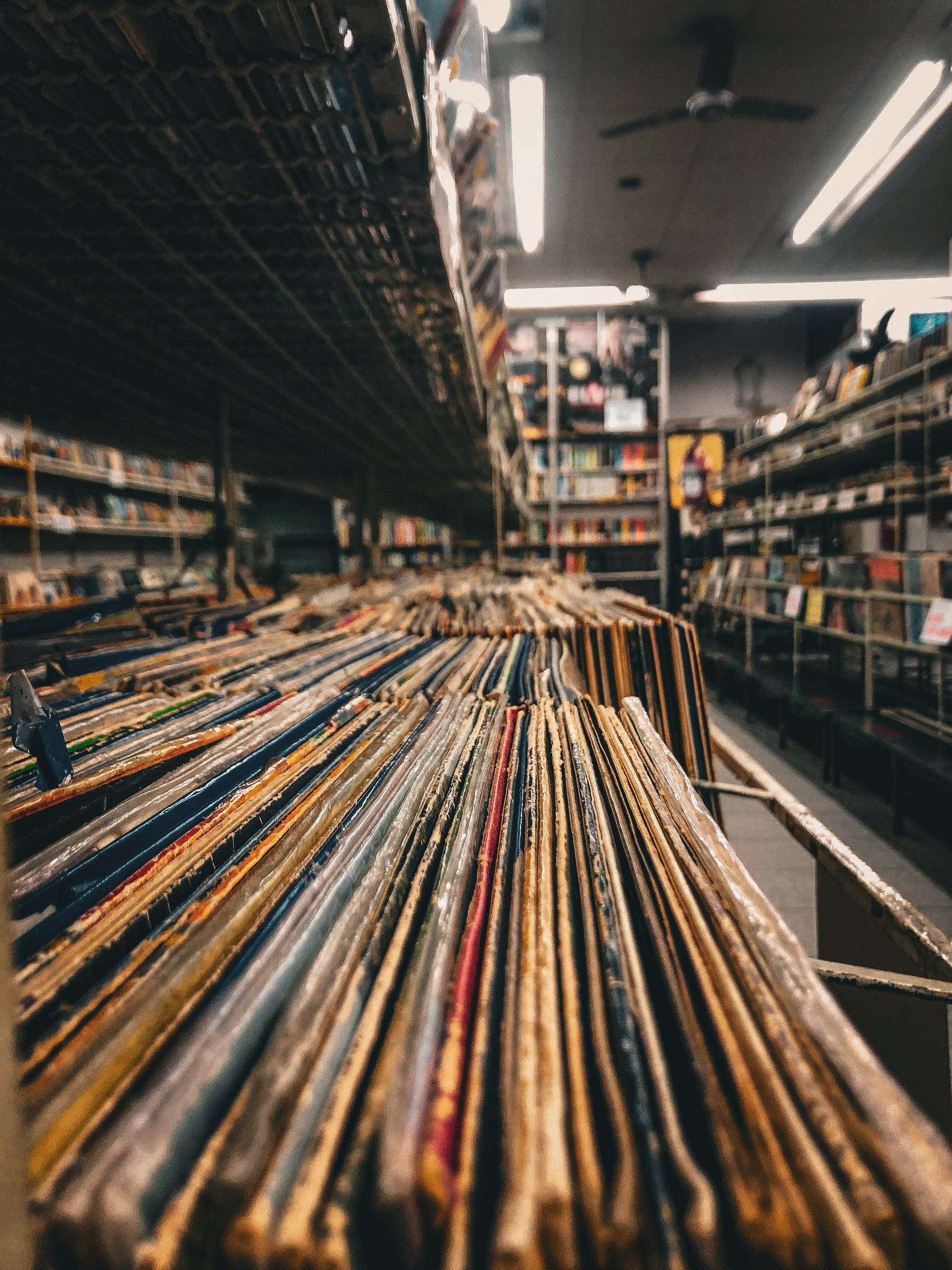 Rows of worn vinyl records in a softly lit independent record shop.